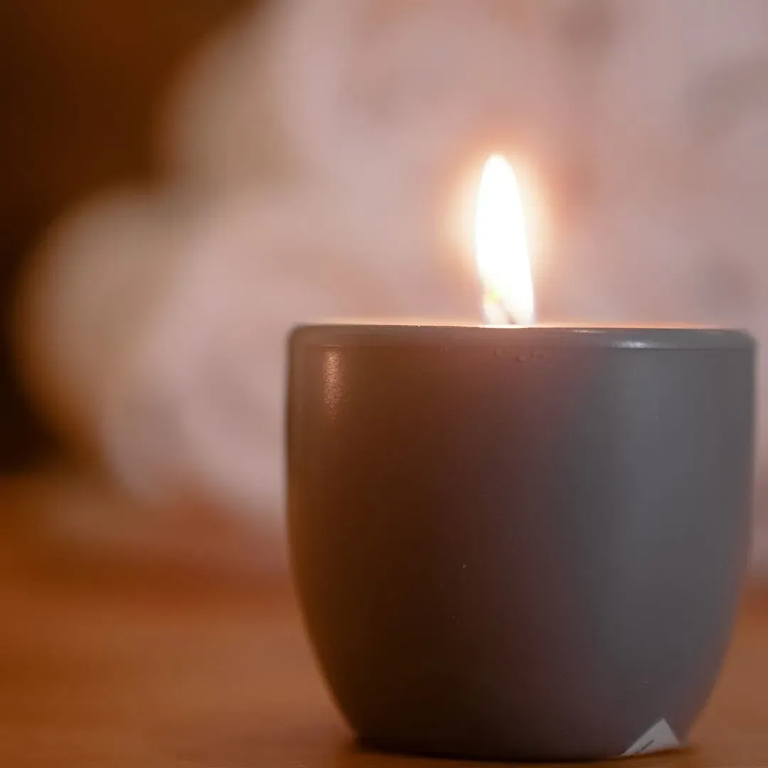 A single lit candle in a grey holder